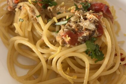 Spaghetti conditi con sugo di pesce, pomodorini, prezzemolo e scorza di limone
